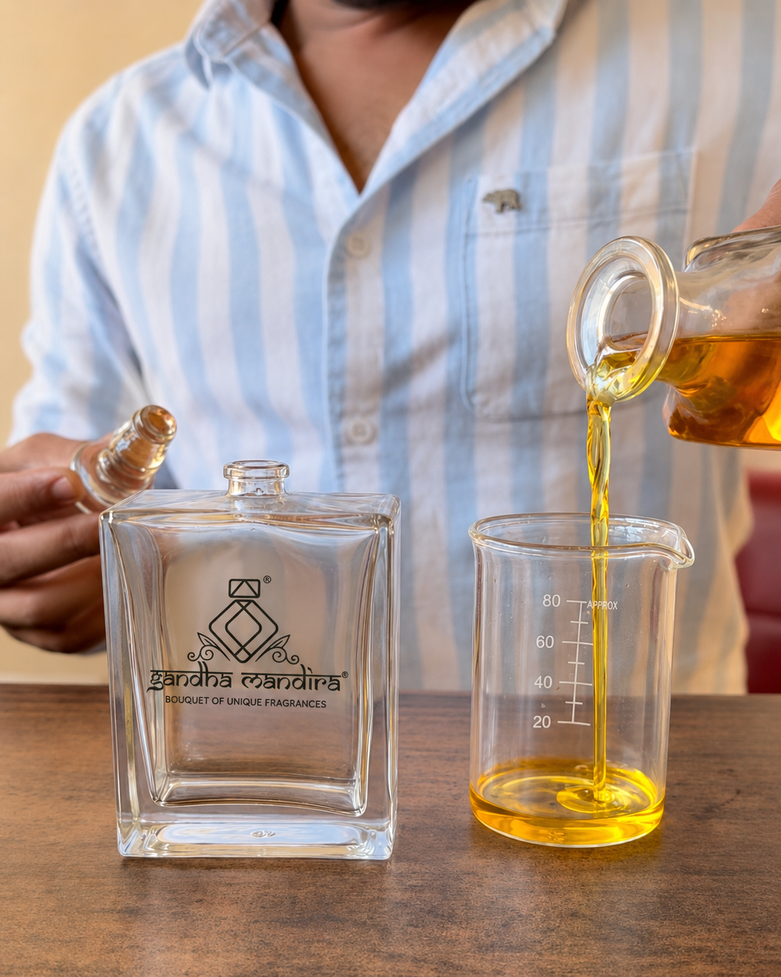 Golden fragrance oil being poured from a decanter into a measuring beaker